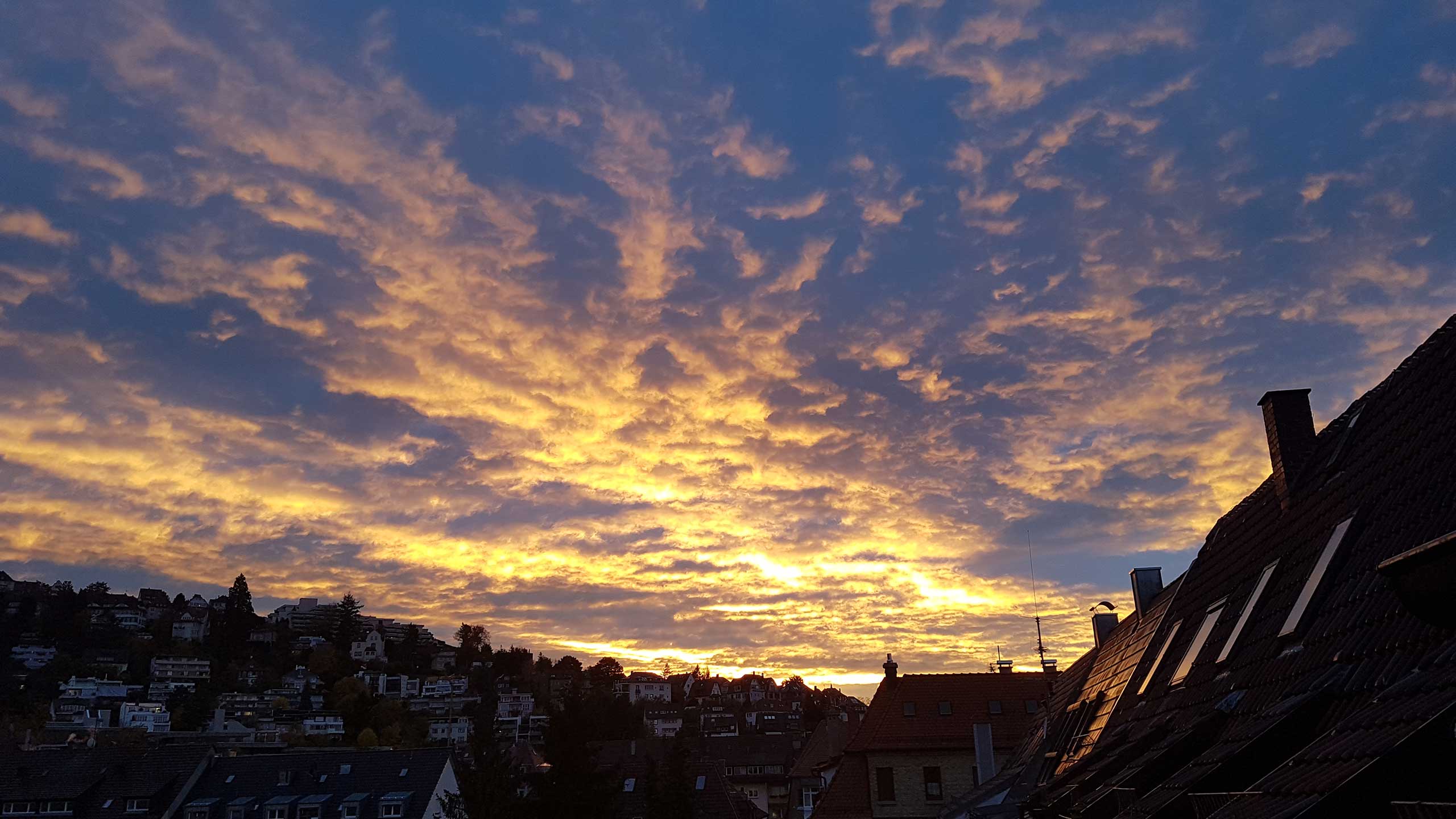 Dunkelblauer Himmel mit von der goldenen Abendsonne angestrahlten Wölkchen. Stuttgart Süd liegt schon im Schatten.. Bild: cc Franziska Köppe | madiko