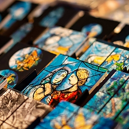 Erinnerungskarten mit Chagall-Fenster-Motiven (Nahaufnahme mit viel Schärfe / Unschärfe). Diese dienen der Schwarmfinanzierung zum Erhalt der Chagall-Fenster und der Kirche.