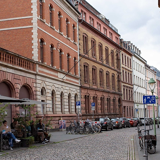 Blick in eine Spielstraße (Breidenbacherstraße) mit alten Ziegelbauten (vierstöckig). Links das Café der Kaffeekommune Mainz mit zahlreichen Fahrrädern und Lastenrädern in unmittelbarer Nähe.