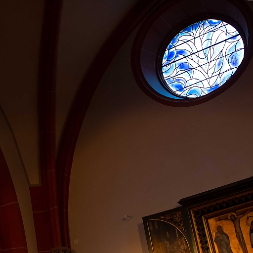 Gotische Bögen und Stelen. Ebenfalls im Blick zwei Chagall-Fenster (links: gotische Rundbogen-Fenster, rechts: Rundfenster mit blaumen, an Wasser erinnernden Mustern)