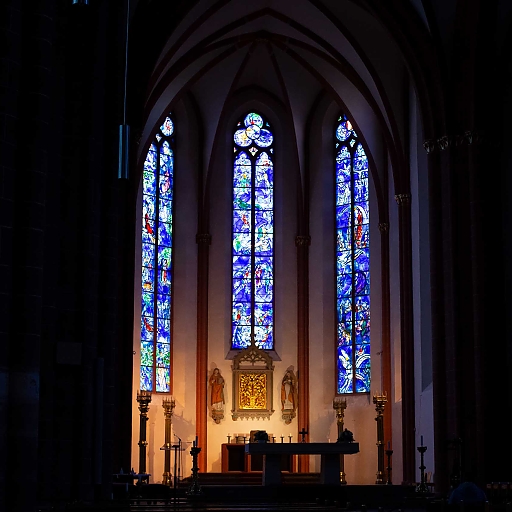 Gotische Rundbogen-Fenster mit Chagall-Motiven in kräftigem Kobalt-Blau, Rot, Occer, Grün mit Motiven aus der Bibel, die die freundlichen Beziehungen zwischen Christen und Juden symbolisieren (hinter dem Altar)