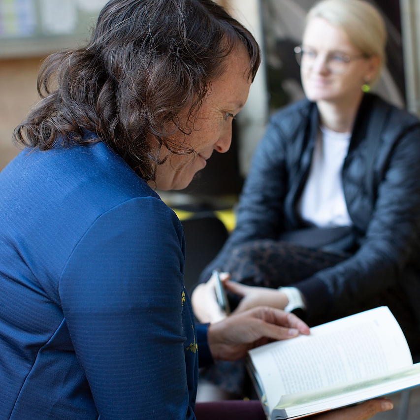 Eine Frau liest in einem Buch. Sie lächelt über den Text.