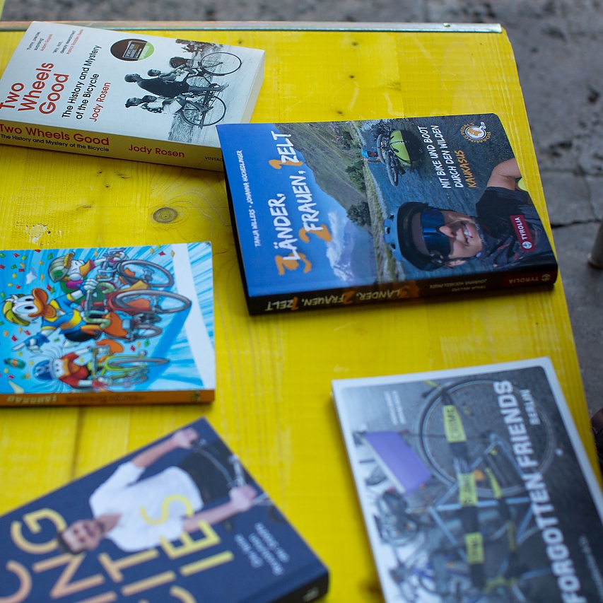 Knall-gelber Tisch. Darauf liegen verschiedene Bücher zum Thema Rad-Fahren: Fahrrad für Kinder, Two Wheels Good, 3 Länder, 2 Frauen, 1 Zelt, Cycling Cities und Forgotten Friends.