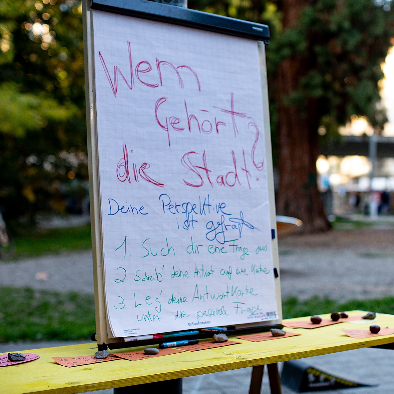 Wem gehört die Stadt? Diese Frage steht auf einem Flip-Chart, der zum Beantworten von Fragen einläd. 