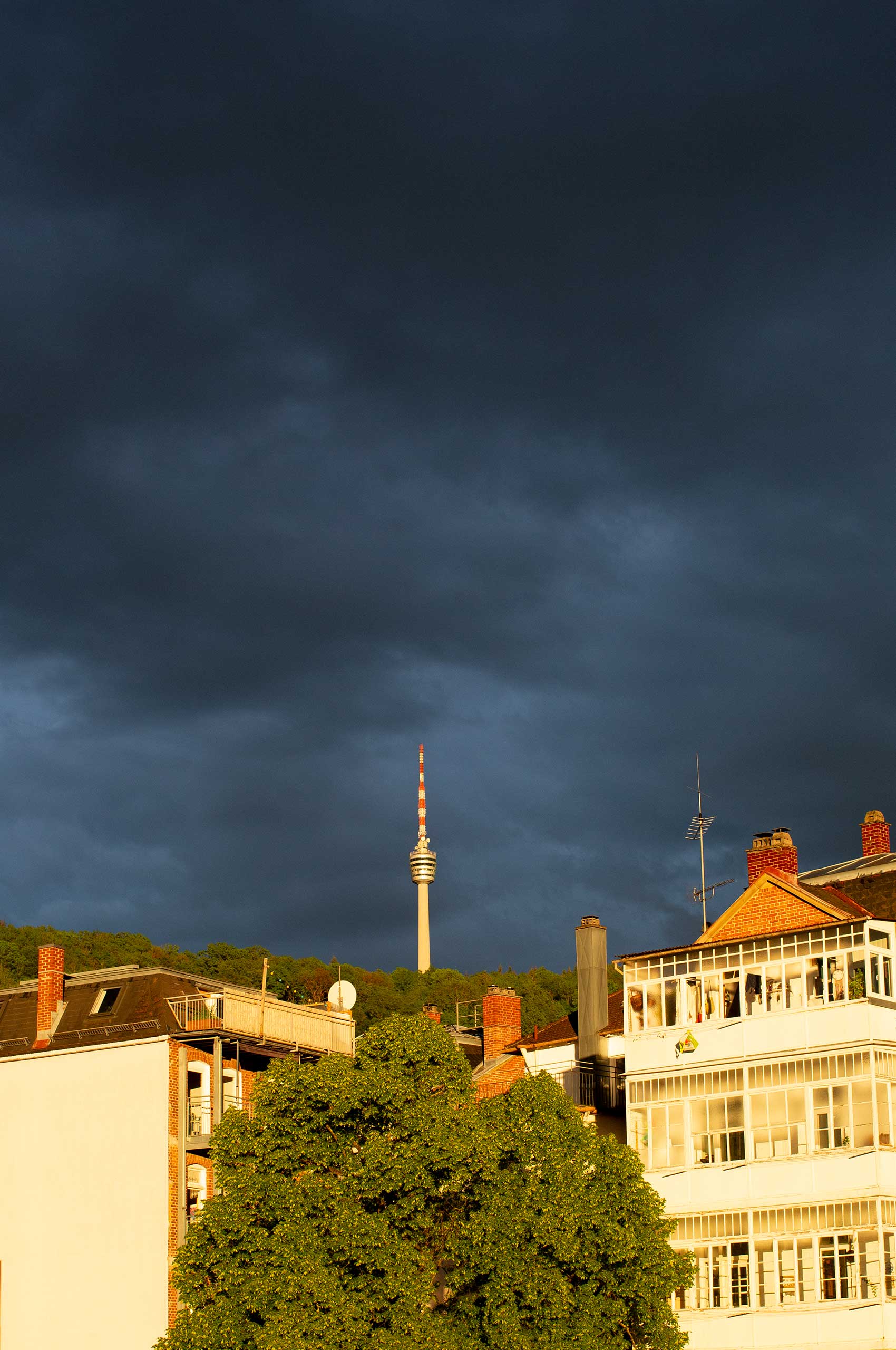 AUTOR: copy | TITLE: Bürofensterblicke: Dramatischer Sonnenuntergang über Stuttgart-Süd | DESCRIPTION: Kräftig dunkelblau-grauer Himmel (Kulisse) und golden angestrahlten Häusern (Vordergrund)
                        