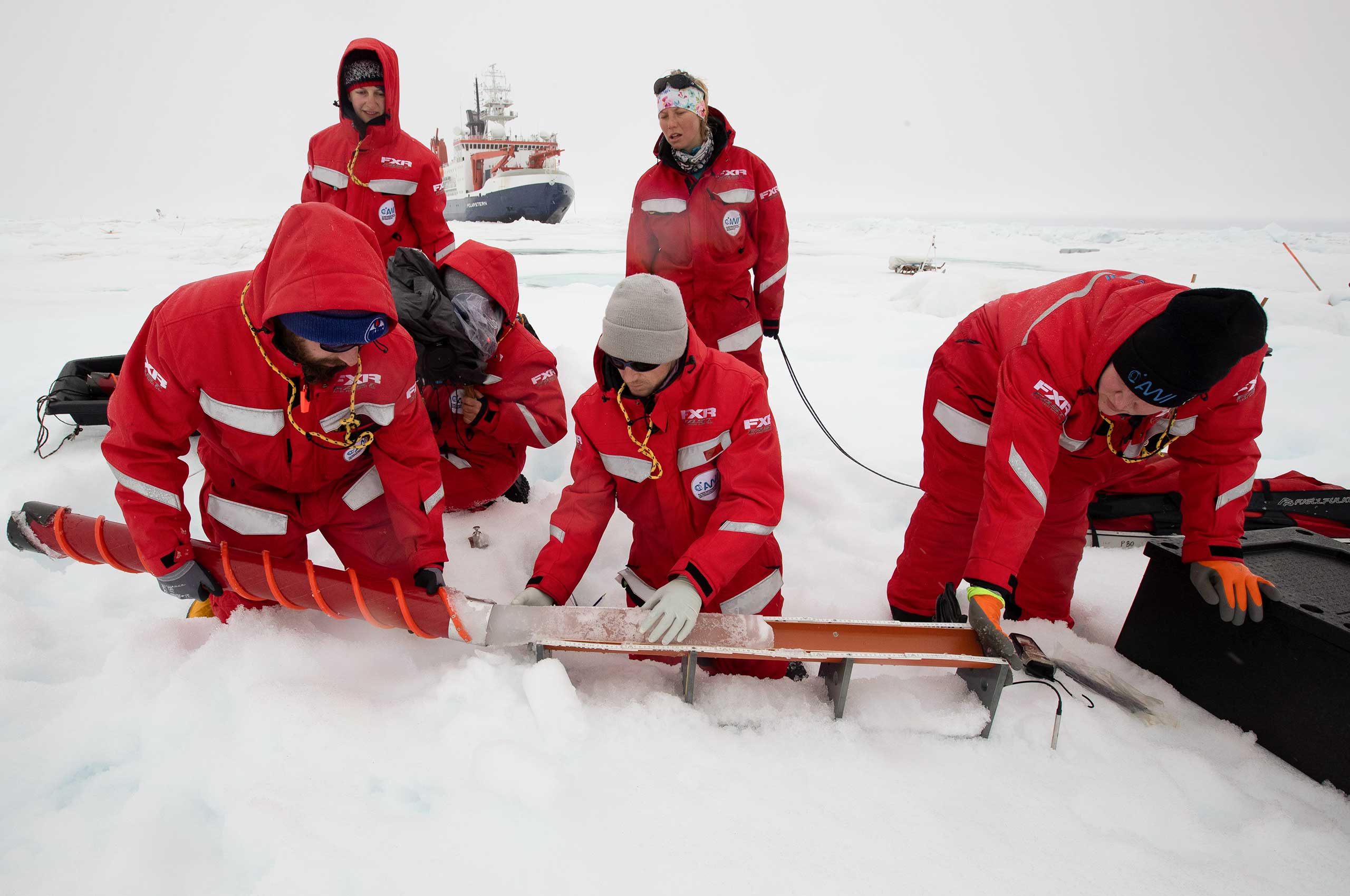 MOSAiC 2019-2020: Forscher:innen nehmen eine Meereis-Kernbohrung am Nordpol vor. Im Hintergrund der Forschungseisbrecher 